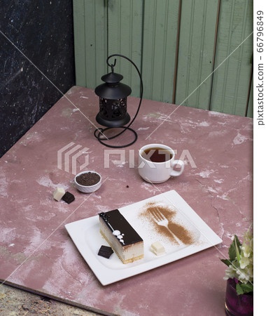 A slice of chocolate cheesecake and a cup of tea on the pink table A slice of chocolate cheesecake and a cup of tea on the pink table 66796849