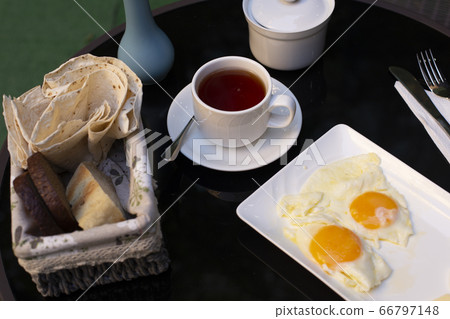 Two fried eggs, a cup of tea and bread 66797148