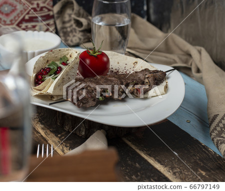 Meat barbecue served with tomato served in lavash 66797149