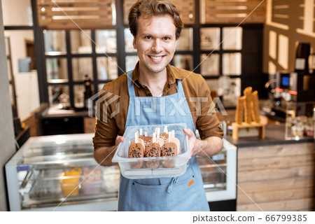 Salesman with chocolate ice cream on a stick in the shop Salesman with chocolate ice cream on a stick in the shop 66799385