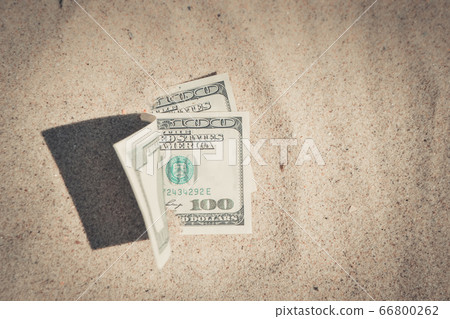 Money dolars half covered with sand lie on beach close-up 66800262