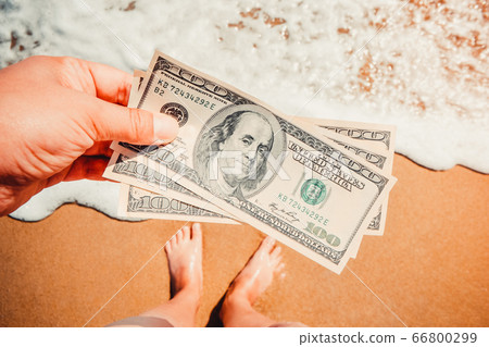 Girl holding money bill of 300 dollars on background of sea ocean Girl holding money bill of 300 dollars on background of sea ocean 66800299
