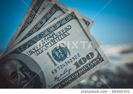 Girl holding money bill of 300 dollars on background of sea ocean Girl holding money bill of 300 dollars on background of sea ocean 66800302