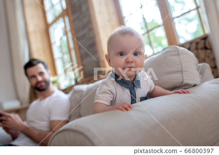 Cute baby crowling , his father watching him and smiling Cute baby crowling , his father watching him and smiling 66800397