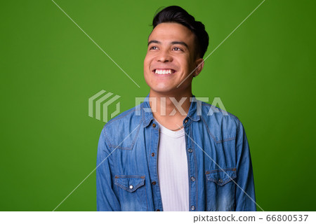 Young multi-ethnic man wearing smart clothing against green background Young multi-ethnic man wearing smart clothing against green background 66800537