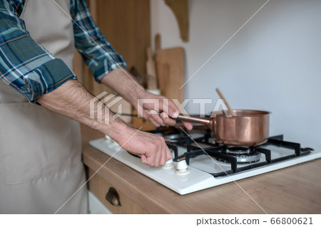 Close up picture of mans hands putting the pan on the oven 66800621