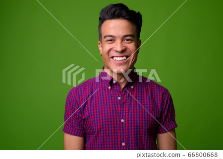 Young multi-ethnic man wearing purple shirt against green background Young multi-ethnic man wearing purple shirt against green background 66800668