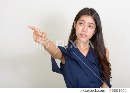 Portrait of young beautiful Asian businesswoman thinking and pointing finger 66801051