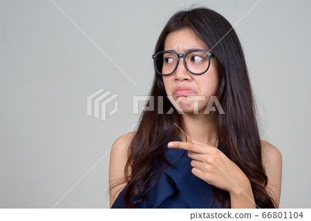 Face of stressed young Asian businesswoman pointing to side and looking disgusted Face of stressed young Asian businesswoman pointing to side and looking disgusted 66801104