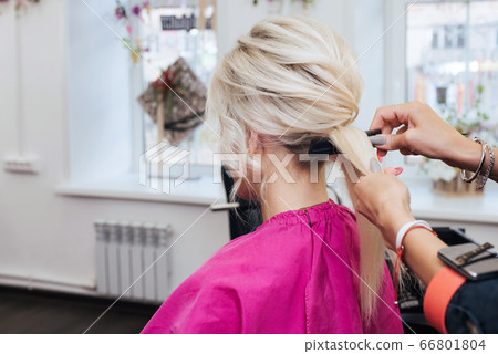 hands of a professional hairstylist make a hairstyle for a blonde girl with long hair hands of a professional hairstylist make a hairstyle for a blonde girl with long hair 66801804