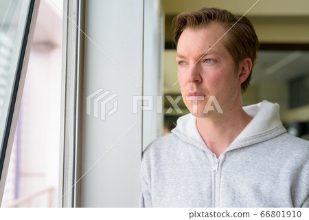 Face of young handsome man thinking and looking out the window at the gym Face of young handsome man thinking and looking out the window at the gym 66801910