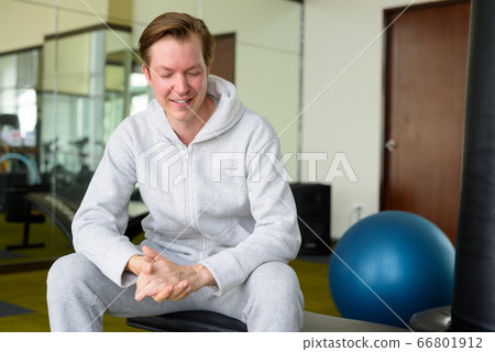 Happy young handsome man with hoodie thinking and sitting at the gym Happy young handsome man with hoodie thinking and sitting at the gym 66801912