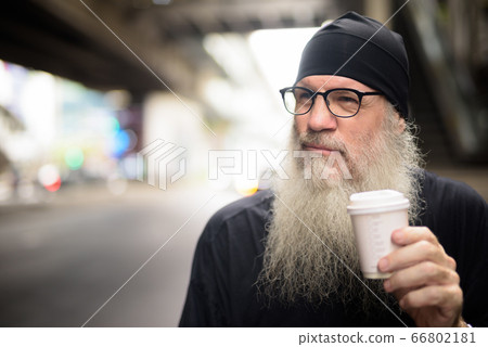 Face of mature bearded hipster man holding paper cup in the city 66802181