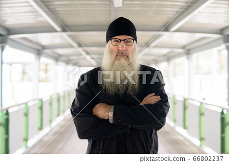 Mature bearded man with arms crossed at footbridge in the city 66802237