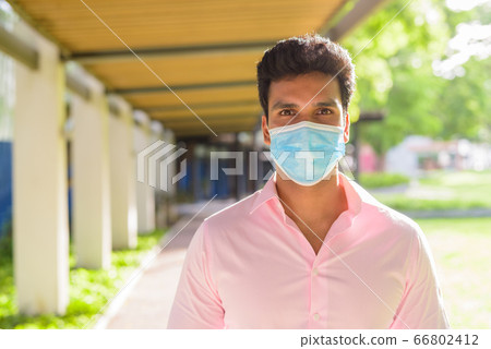 Face of young Indian businessman with mask for protection from corona virus outbreak at the park 66802412