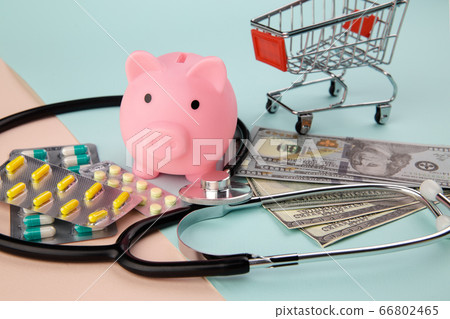 Health care cost concept. Stethoscope and drugs, piggy bank and dollars money banknotes on colorful background Health care cost concept. Stethoscope and drugs, piggy bank and dollars money banknotes on colorful background 66802465