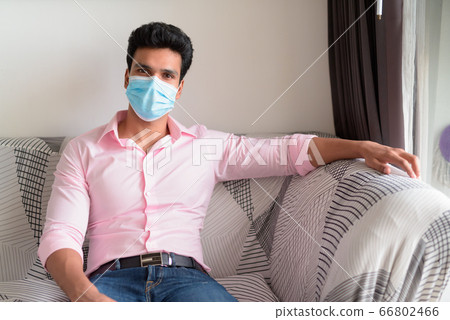 Young Indian businessman with mask staying at home under quarantine Young Indian businessman with mask staying at home under quarantine 66802466