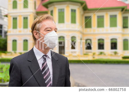 Face of mature businessman with mask for protection from corona virus outbreak thinking in the city Face of mature businessman with mask for protection from corona virus outbreak thinking in the city 66802758