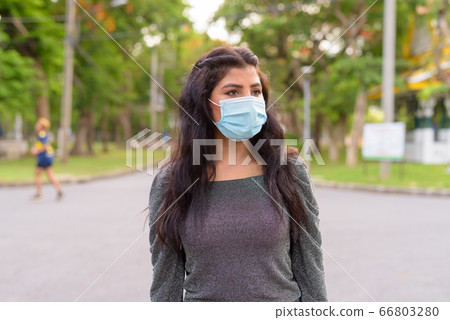 Young Indian woman with mask thinking at the park outdoors 66803280