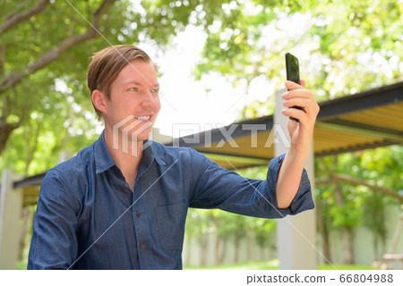 Face of happy young handsome blond businessman taking selfie at the park outdoors Face of happy young handsome blond businessman taking selfie at the park outdoors 66804988