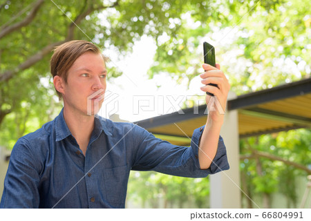 Face of young handsome blond businessman taking selfie at the park outdoors Face of young handsome blond businessman taking selfie at the park outdoors 66804991