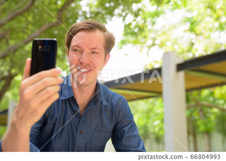 Face of happy young handsome blond businessman taking selfie at the park outdoors Face of happy young handsome blond businessman taking selfie at the park outdoors 66804993