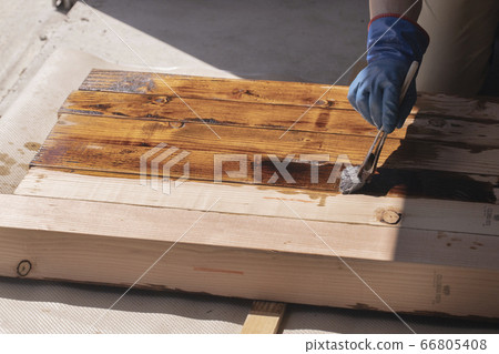 A carpenter painting insect repellent on a large drawing material 66805408