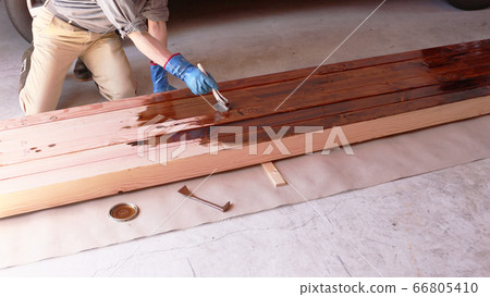 A carpenter painting insect repellent on a large drawing material 66805410