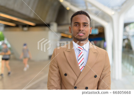 Happy young handsome African businessman smiling at the footbridge 66805668