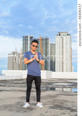 Full body shot of young handsome multi ethnic man with sunglasses against view of the city 66806337
