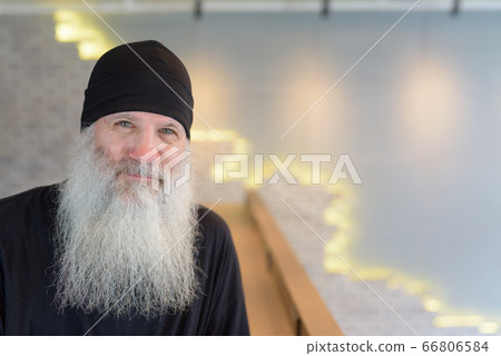 Face of mature handsome bearded hipster man wearing beanie hat indoors 66806584