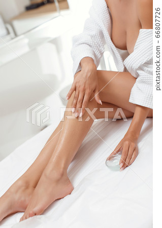 Young woman applying body lotion on legs Young woman applying body lotion on legs 66807726