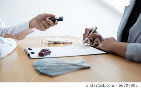 The car salesman handed the keys to the customer who passed the car purchase loan conditions ,Car rental agreement Concept. The car salesman handed the keys to the customer who passed the car purchase loan conditions ,Car rental agreement Concept. 66807908