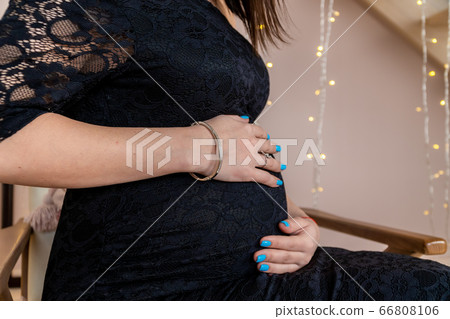 Russia, Saint Petersburg. A pregnant woman gently supports her tummy with her hands. Russia, Saint Petersburg. A pregnant woman gently supports her tummy with her hands. 66808106