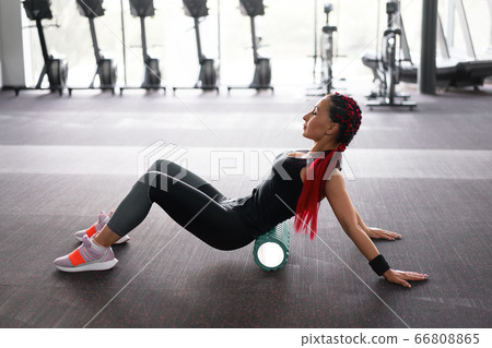 Woman massaging foam roll leg gym myofascial Woman massaging foam roll leg gym myofascial 66808865