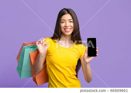 Shopping App. Asian Girl Holding Smartphone With Black Screen And Shopper Bags 66809661