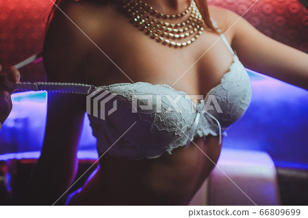 black bra being remove by a man hand. 66809699