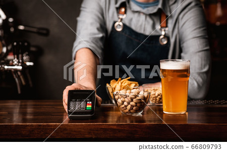 Bartender serves glass of beer, snacks and modern terminal Bartender serves glass of beer, snacks and modern terminal 66809793