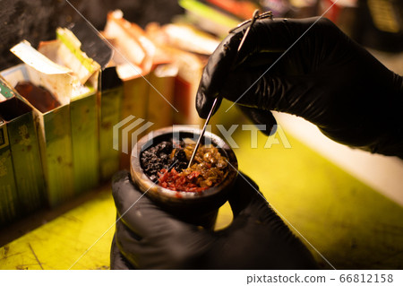 Preparation of Hookah bowl with tabacco leaf hands Preparation of Hookah bowl with tabacco leaf hands 66812158
