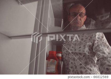 Hungry man looking for a late night meal in an empty fridge. Senior man looking for a snack in the fridge at night, view from the fridge 66812569