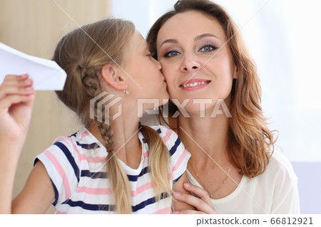 Cute little girl kissing mother in cheek 66812921