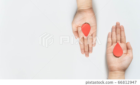 Blood donation - Human hand giving blood drop symbol to a hand on white background. World blood donor day and save life concept. Flat lay. Copy space. 66812947