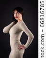 Woman in beige tight dress on black 66816785