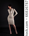 Woman in beige tight dress on black 66816787