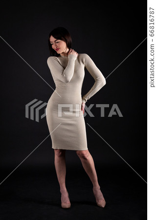 Woman in beige tight dress on black 66816787