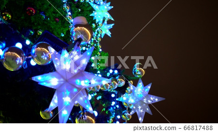 Panoramic view multi-colored garlands, balls and stars decorated Christmas tree on square Panoramic view multi-colored garlands, balls and stars decorated Christmas tree on square 66817488