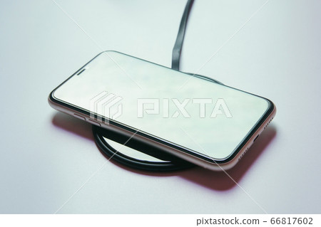 Smartphone charging on a wireless charger Smartphone charging on a wireless charger 66817602