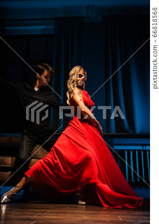 Dance and love concept. Young couple in elegant evening dresses posing in the room filled with dramatic light. Two dancers man and woman holding each other in passionate pose Dance and love concept. Young couple in elegant evening dresses posing in the room filled with dramatic light. Two dancers man and woman holding each other in passionate pose 66818568