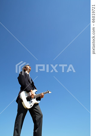 High school boy playing electric guitar outdoors against blue sky 66819721