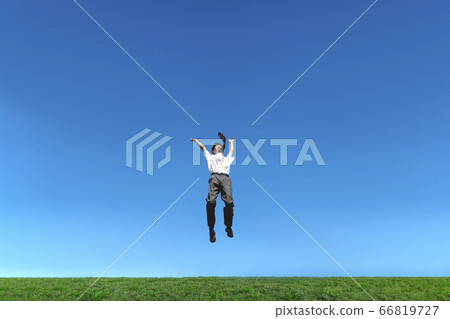 Male high school student jumping while happily against the blue sky Male high school student jumping while happily against the blue sky 66819727